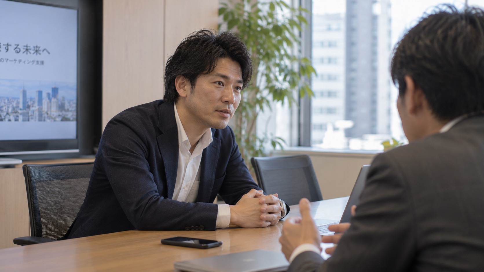 営業・サービス：営業担当者が顧客の話に身を乗り出して集中しながら商談し、テーブルのスマホが録音中で、商談後にAIが議事録と次アクションを自動生成する場面